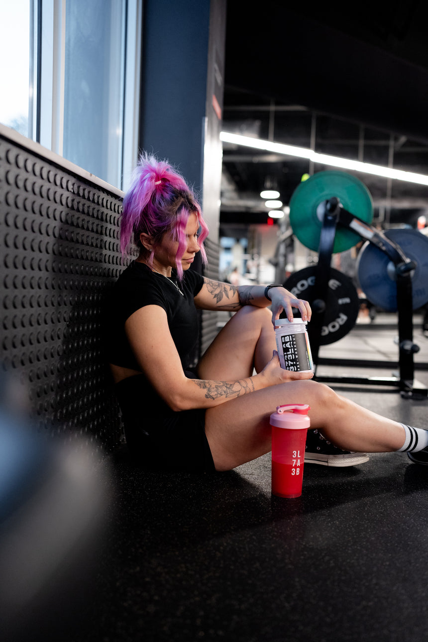 woman sitting at the gym taking 373 lab supplements